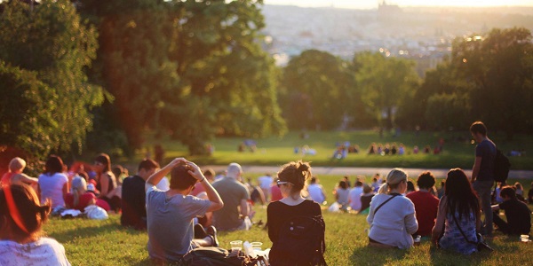 Menschen sitzen auf einem Gr&uuml;nstreifen im Sonnenschein