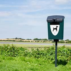 Papelera para residuos caninos Terrier 25 &trade; poste montado en un camino rural