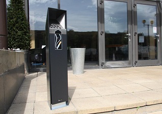 Cendrier d’extérieur Ashguard™ sur pied à l'extérieur d'un bâtiment professionnel