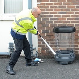 A Glasdon working hitting a C-Thru Litter Bin with a baseball bat to test its strength