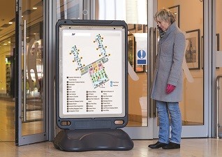 Advocate™ Freestanding Poster Display Sign with conference facility map with reference points and lady looking at sign