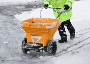 Turbocast™ 300 manual salt spreader in yellow on snowy grounds