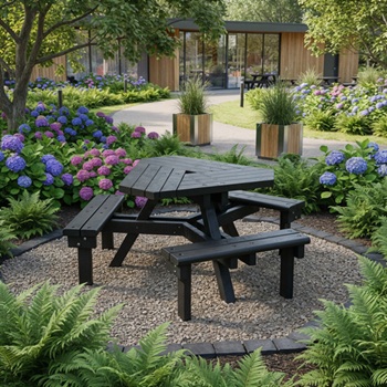 A triangular picnic table allowing easy access from all sides, in a nice plaza or backyard, surrounded by foliage, near a nice path, with a building in the background