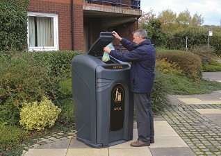 Nexus® City 240 afvalbak in zwart met man die afval deponeert