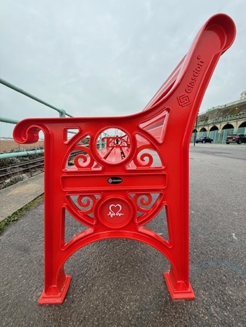 closeup of the side of a red british heart foundation bench with a Glasdon engraving