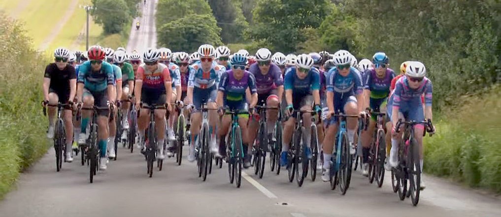 a row of cyclists engaged in an uphill race on a rural road