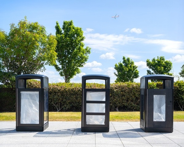 origin vision, origin insight, and origin aspect transparent security bins on pavement with an aeroplane flying overhead