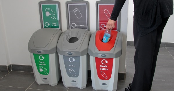 Someone recycling a bottle using a plastic bottle recycling bin