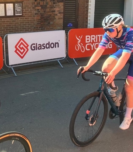 cyclist in the lincoln grand prix riding next to a barrier with a glasdon logo