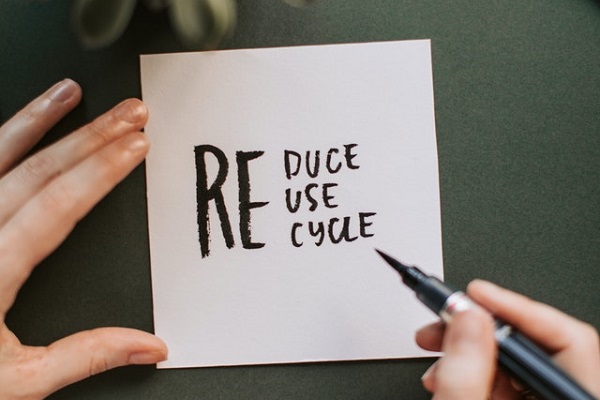 A post-it note with reduce, reuse, recycle written on it in black pen