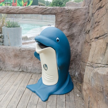 A large bin shaped like a dolphin in a zoo next to an aquatic animal&rsquo;s habitat